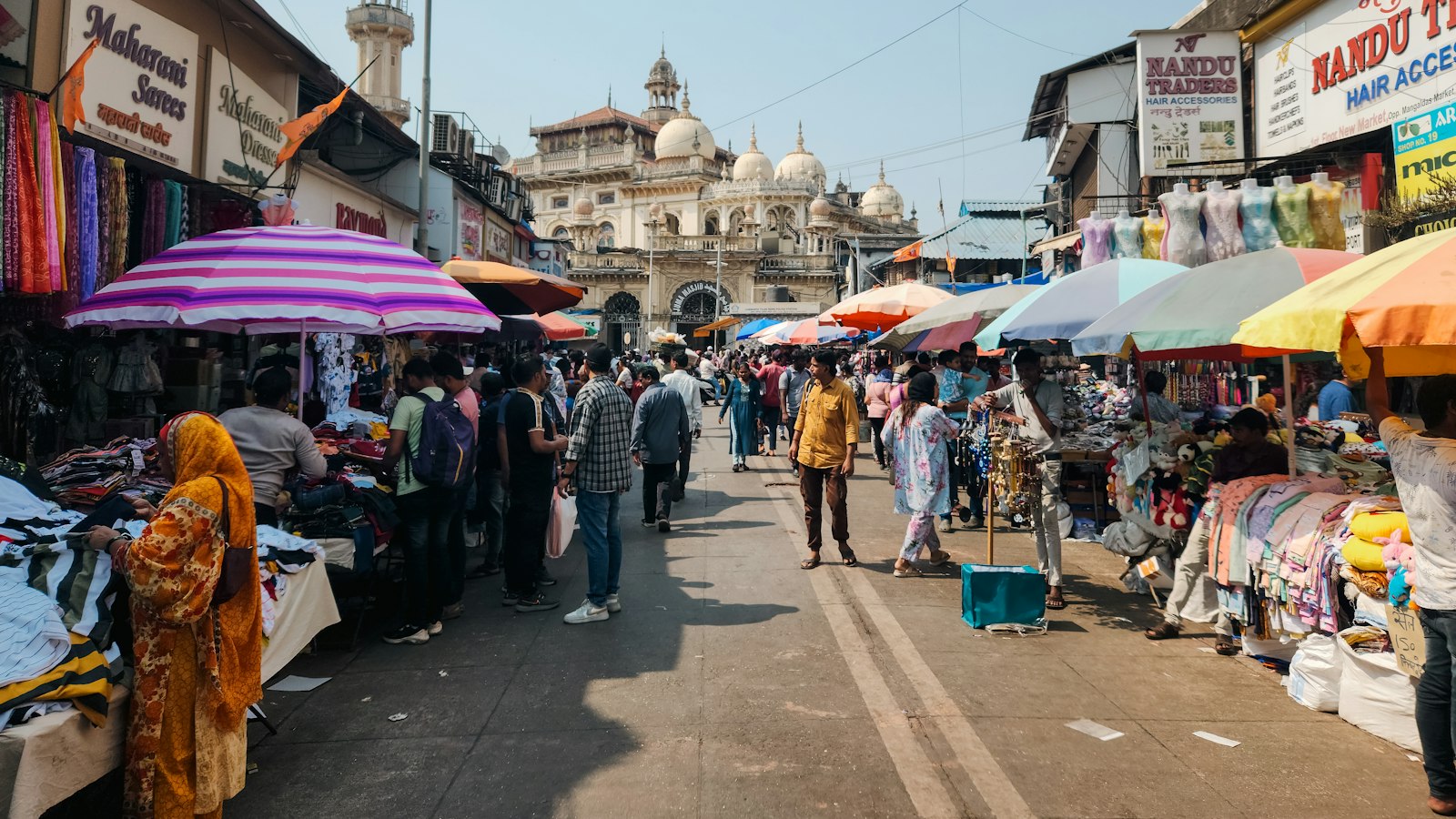 A group of people walking down a street next to shops