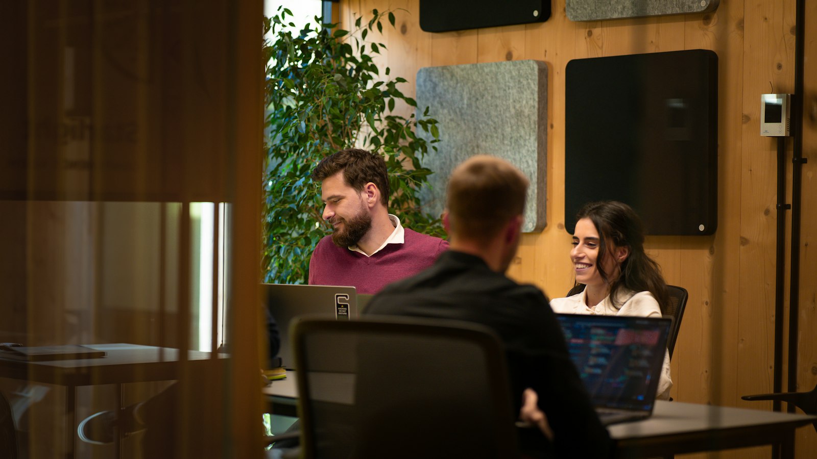 A group of people sitting around a table with laptops
